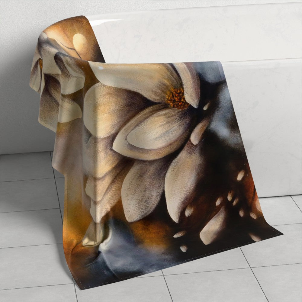 Flourishing in the Light — Beach Towel by Annikaprana, draped against a white bathroom wall. Close-up of magnolia flower detail, edge-to-edge dye sublimation print, 70×140 cm.
