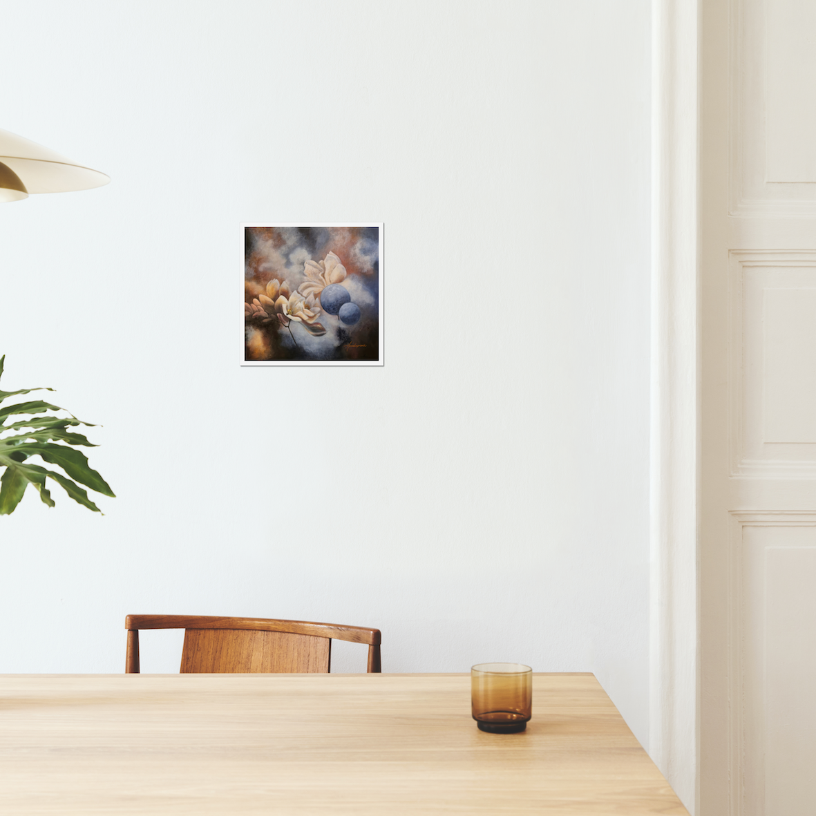Finding the Light — Fine Art Print by Annikaprana. Soft magnolia blossoms in warm golden and dusty blue tones against a dreamy, atmospheric background. Giclée on Hahnemühle German Etching 310gsm, white border, 12×12″ (≈30×30 cm). Displayed on a white wall in a Scandinavian dining room.